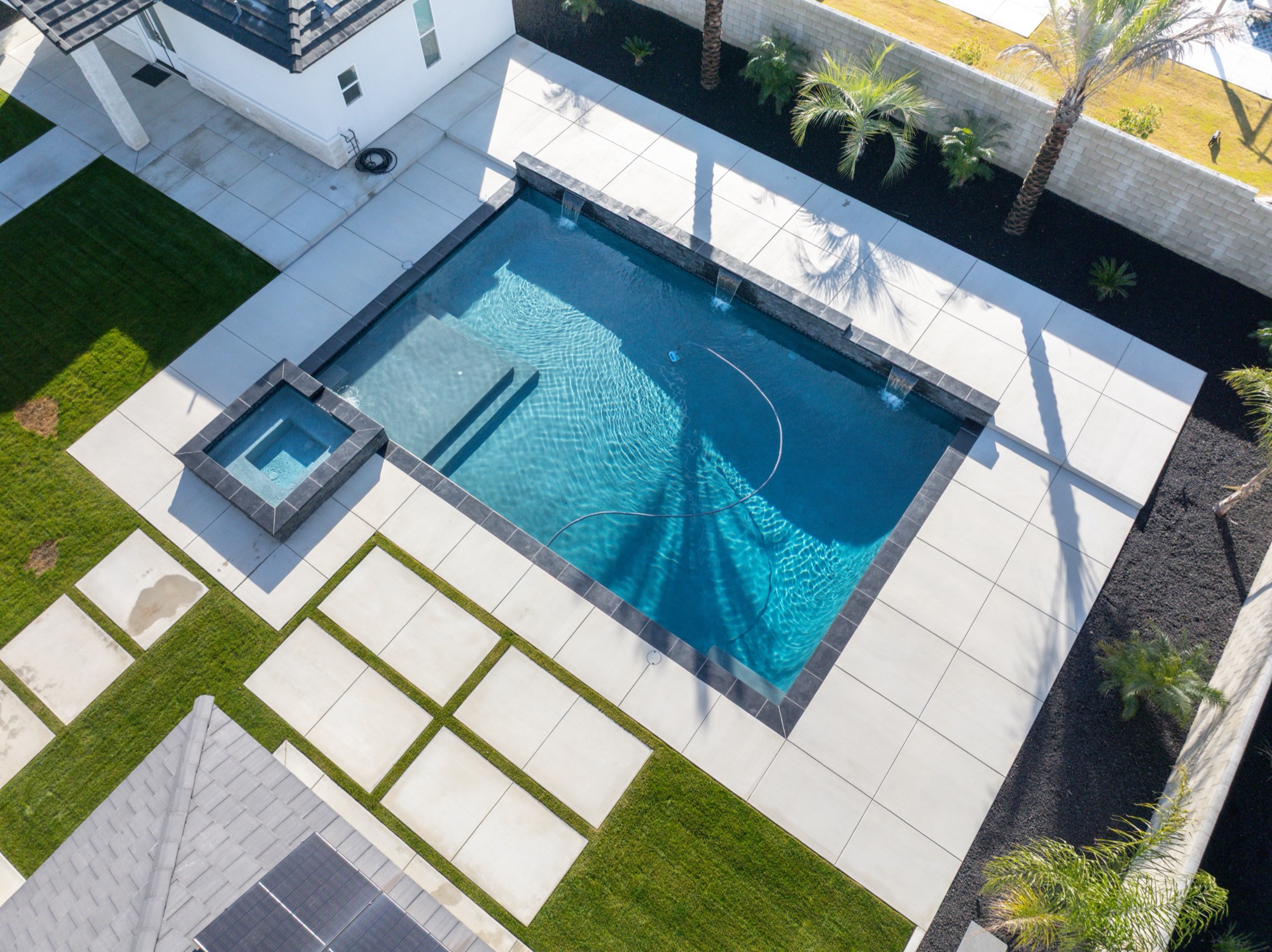 Aerial view of custom gunite pool with modern white home and spa in Bakersfield