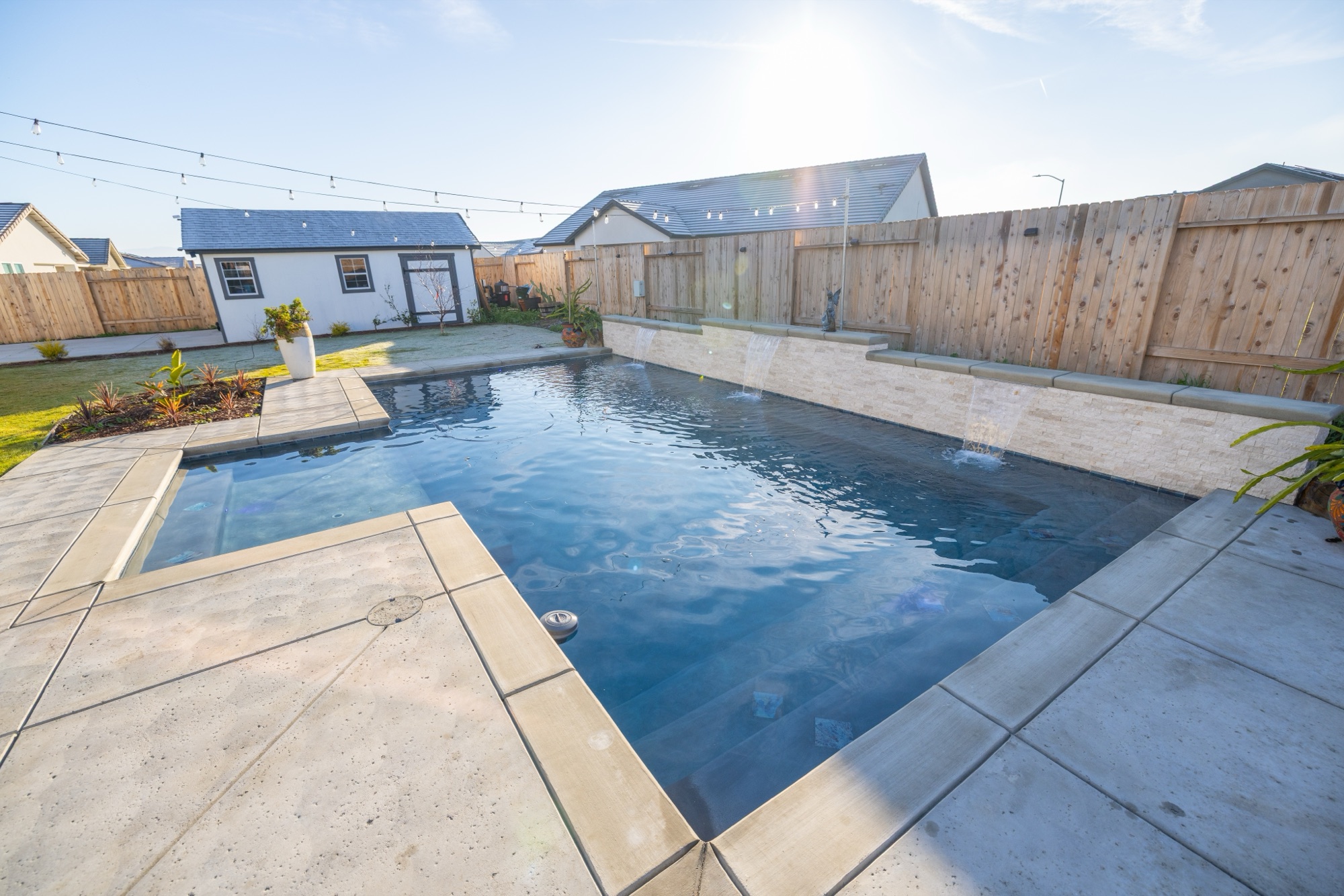 Custom gunite pool with dark plaster finish and stone wall in Bakersfield
