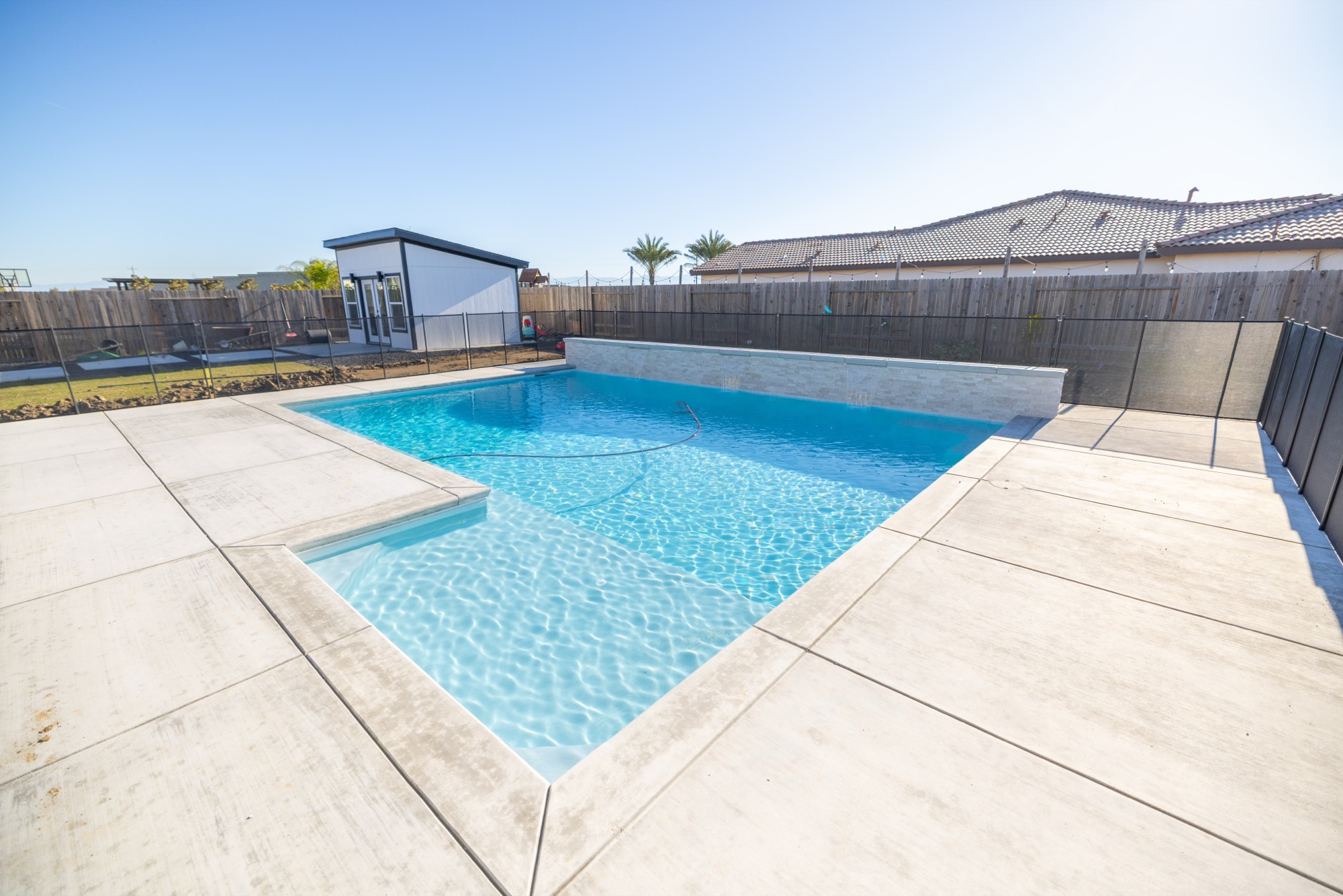 Custom gunite pool with white plaster finish and sunny concrete deck